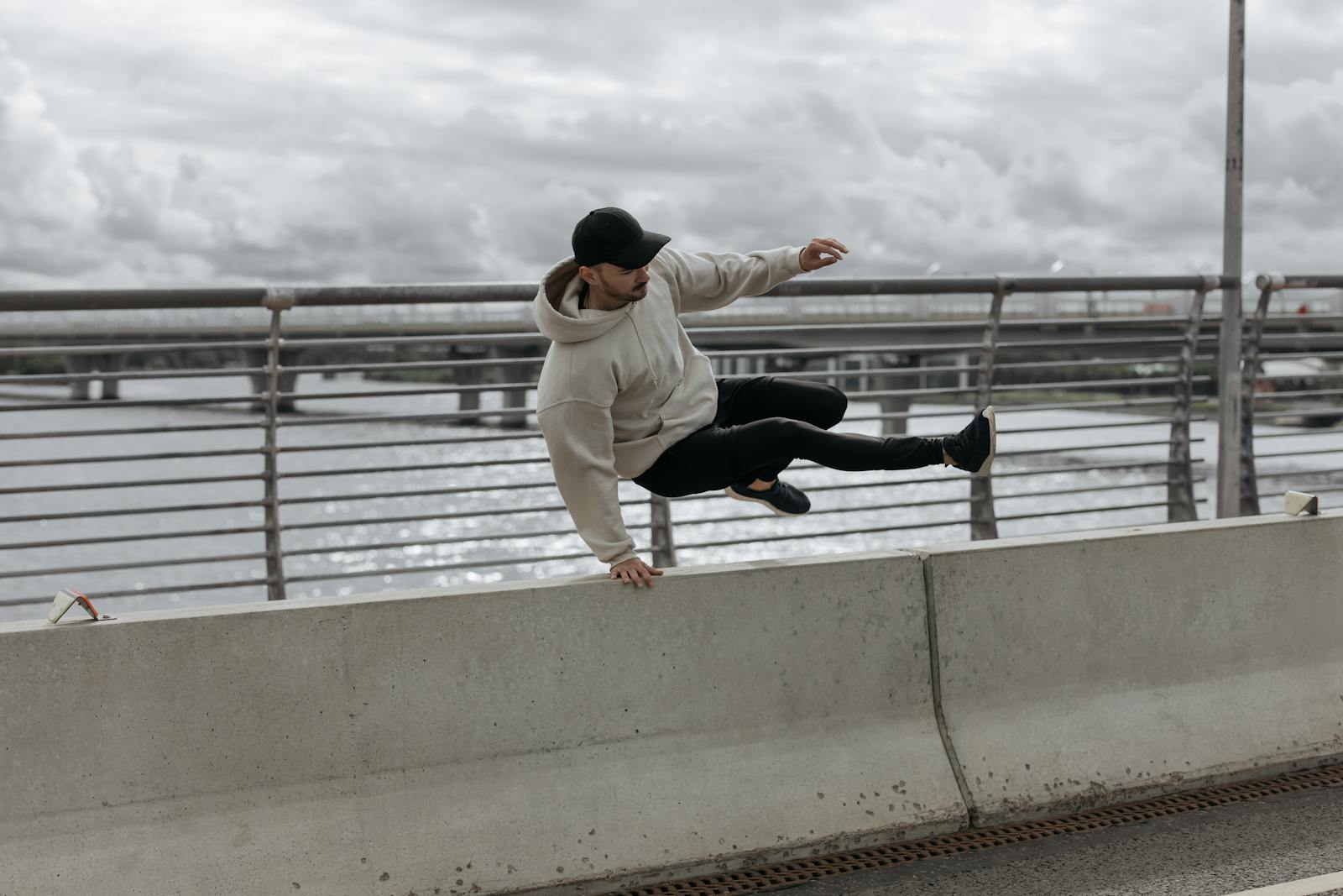 A Man wearing Cap Jumping on the Barrier