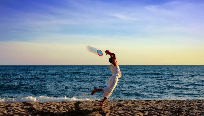 Man Jumping For Frisbee on the Beach